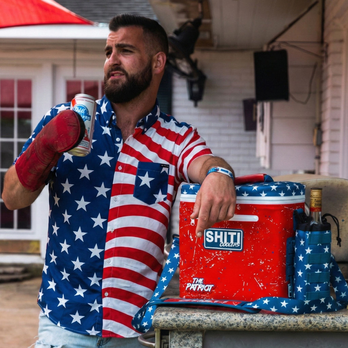 Man wearing a patriotic Spread Eagle Party Shirt stands by a cooler, holding a drink and showcasing a festive party vibe.