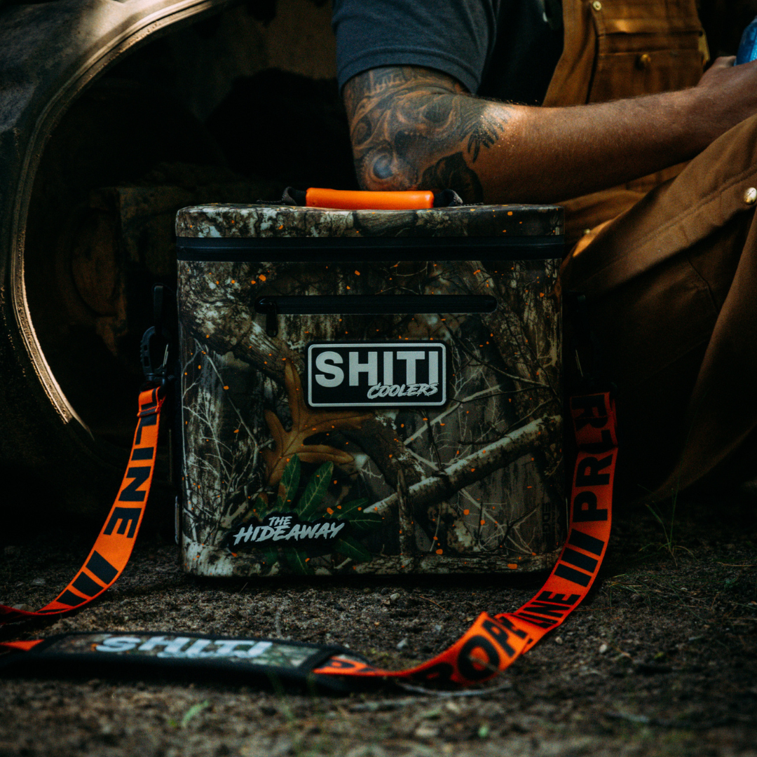 Realtree Soft Cooler designed to hold 12 cans, featuring a camo pattern and a durable strap for easy transport.