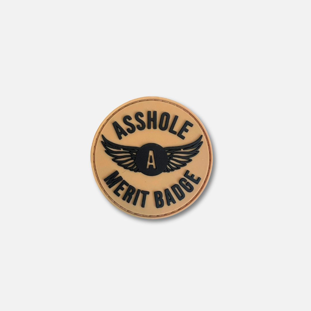 Round Velcro patch featuring the text &quot;ASSHOLE MERIT BADGE&quot; with wings, designed for fun and humor.