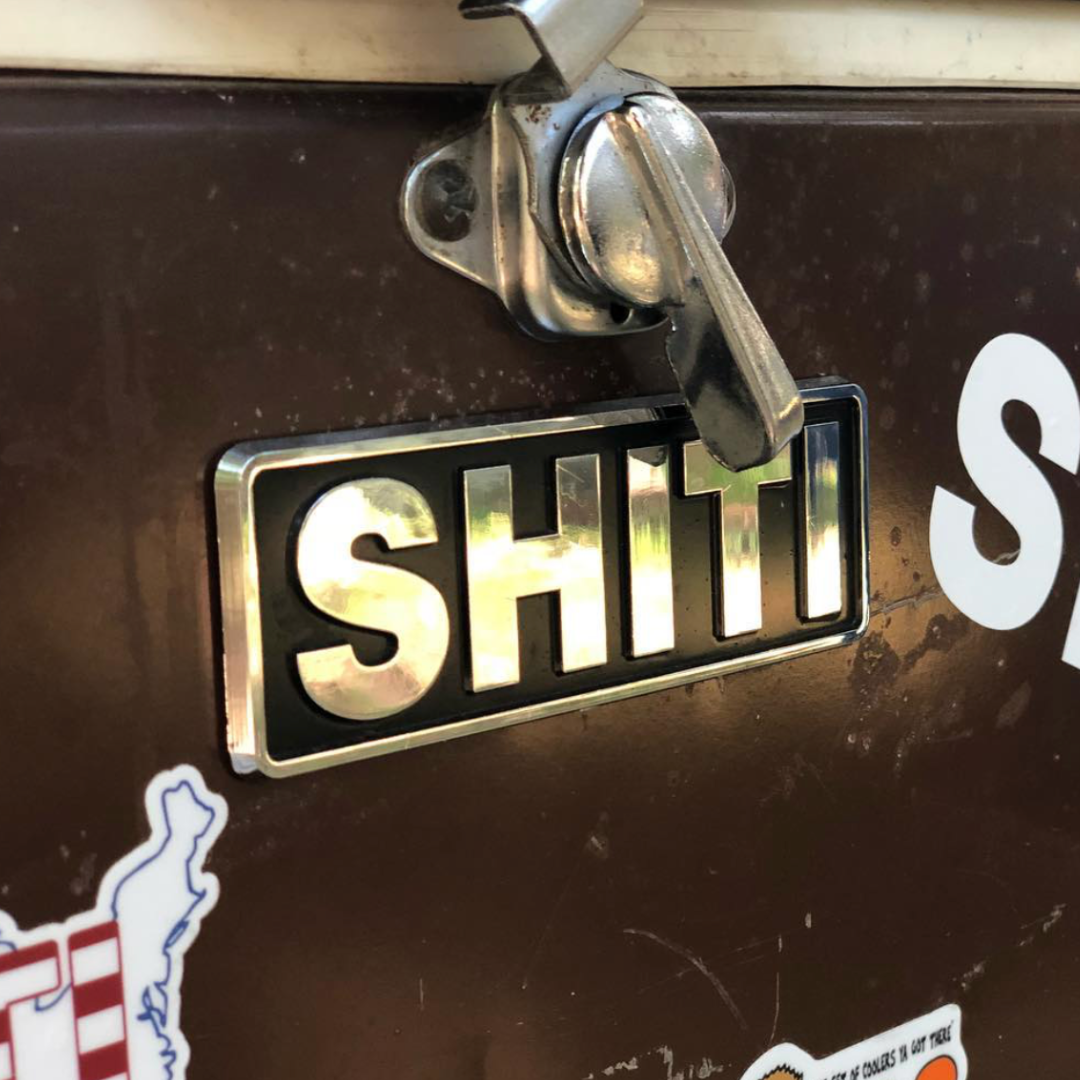 Chrome brand plate featuring the word &quot;SHITI&quot; mounted on a cooler, showcasing a sleek and shiny design.