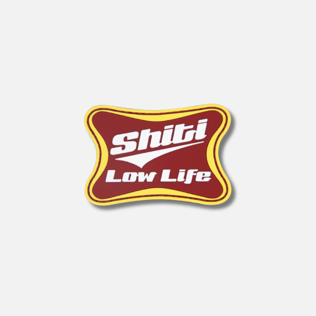 Velcro patch featuring the text &quot;Shiti Low Life&quot; in bold white letters on a maroon background with a yellow border.